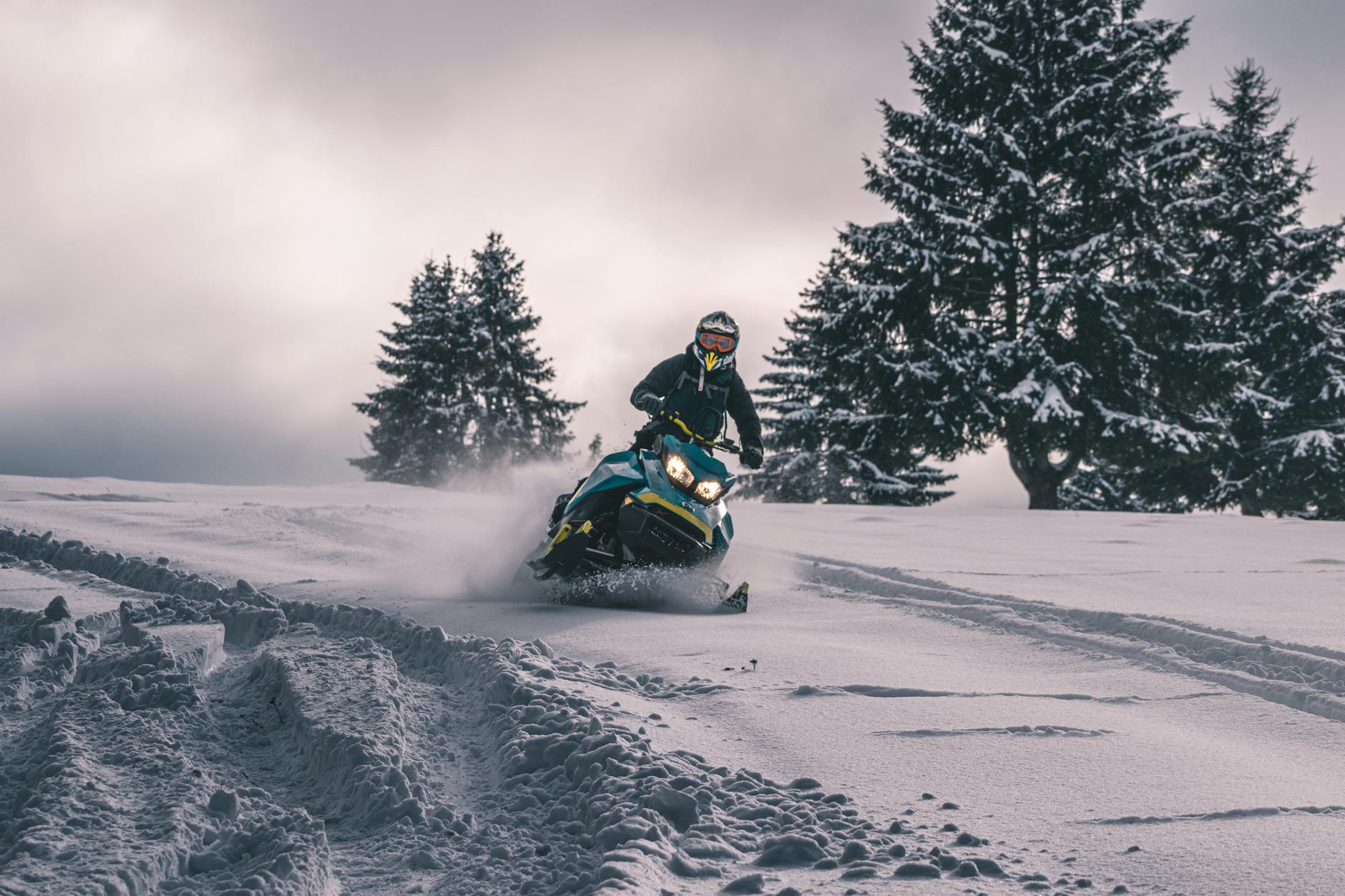 Snowmobile rider crossing a snowy hill