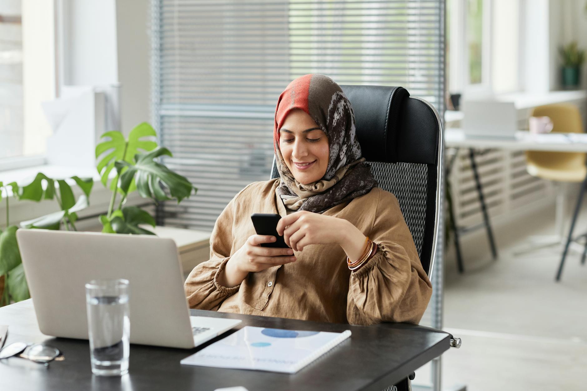 Businesswoman checking messages beside a laptop