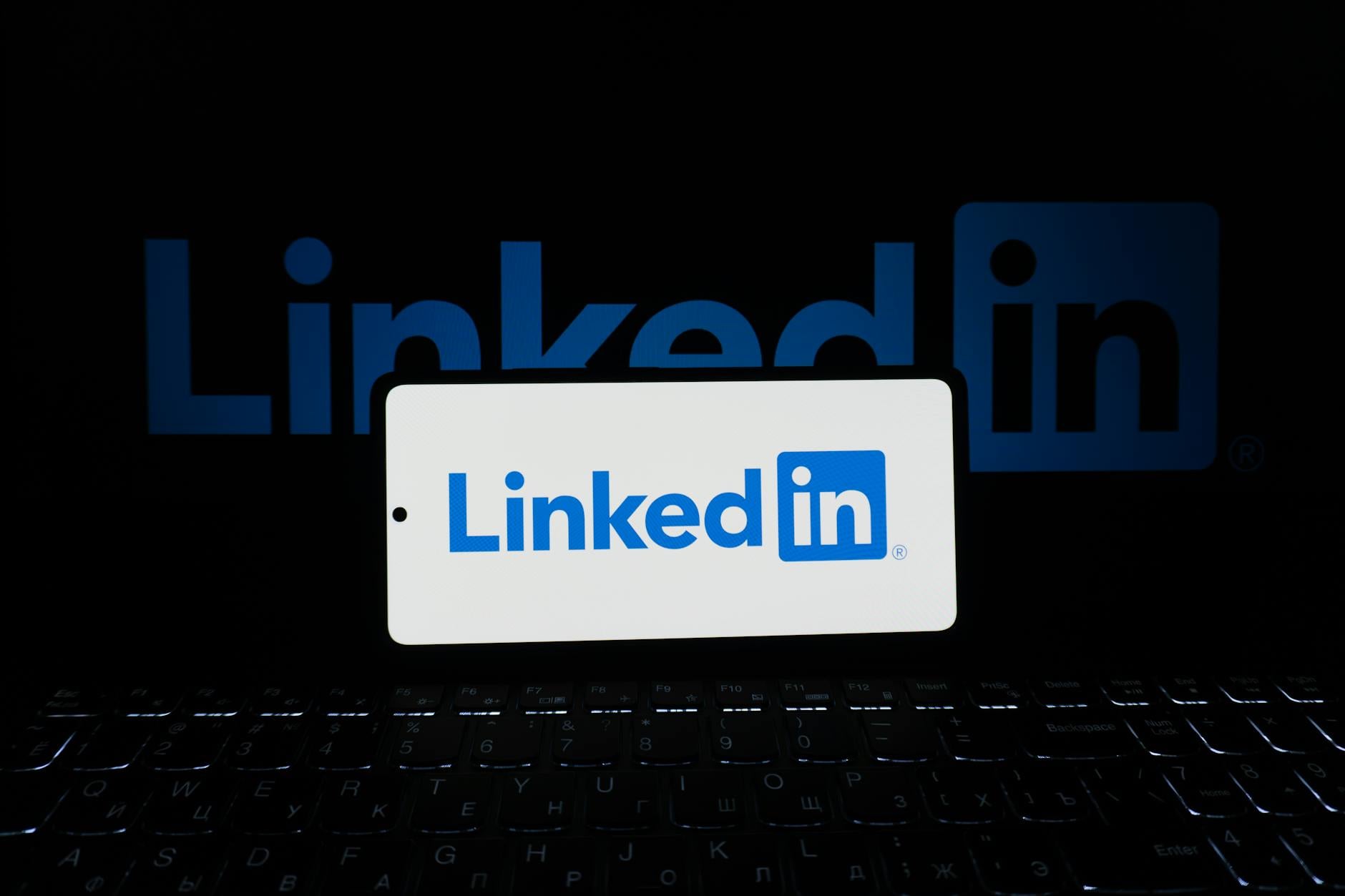 Smartphone showing LinkedIn beside a laptop keyboard