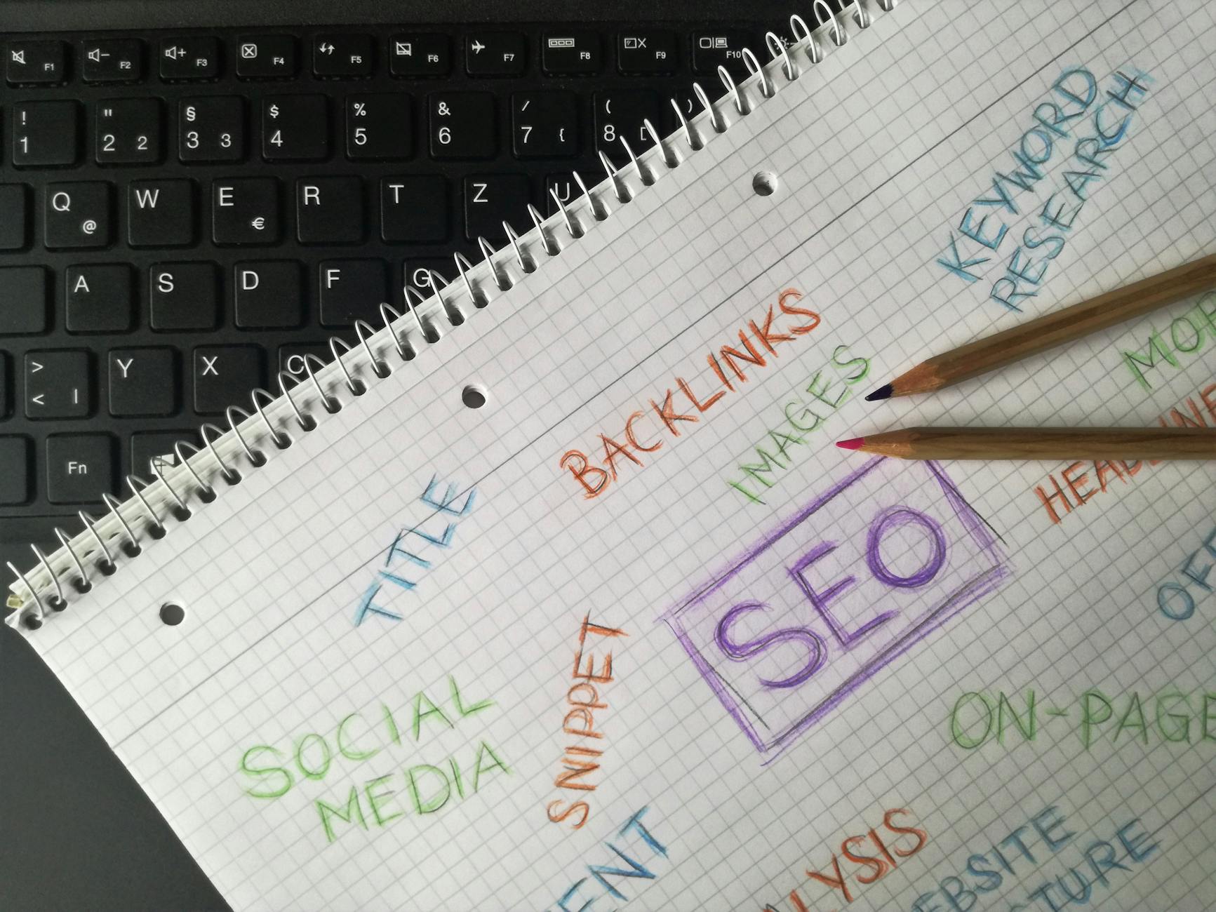 Notebook with SEO keyword notes beside a laptop